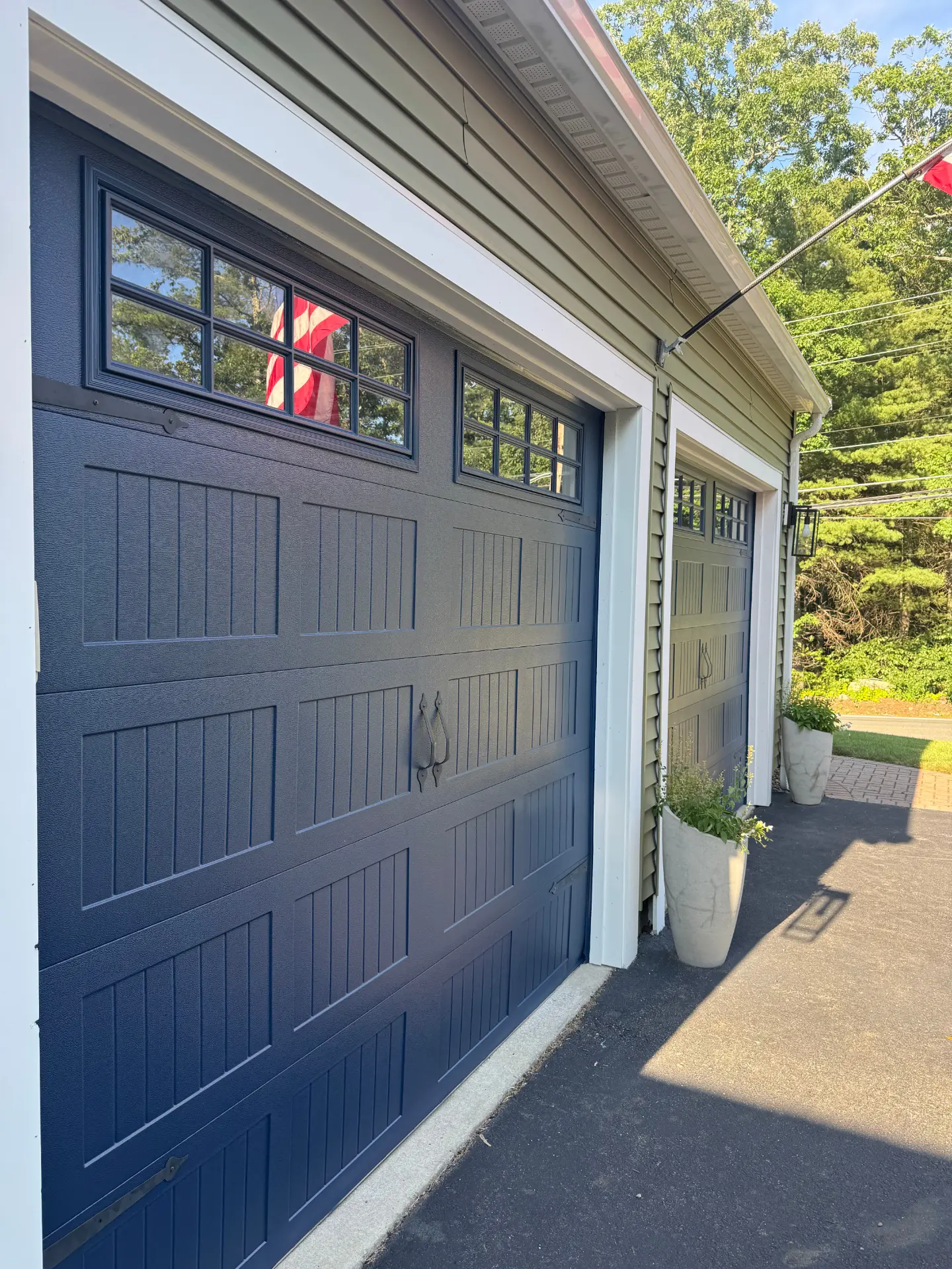 Exterior garage doors and trim freshly painted in deep navy with crisp white casing by Elite Brothers Painting