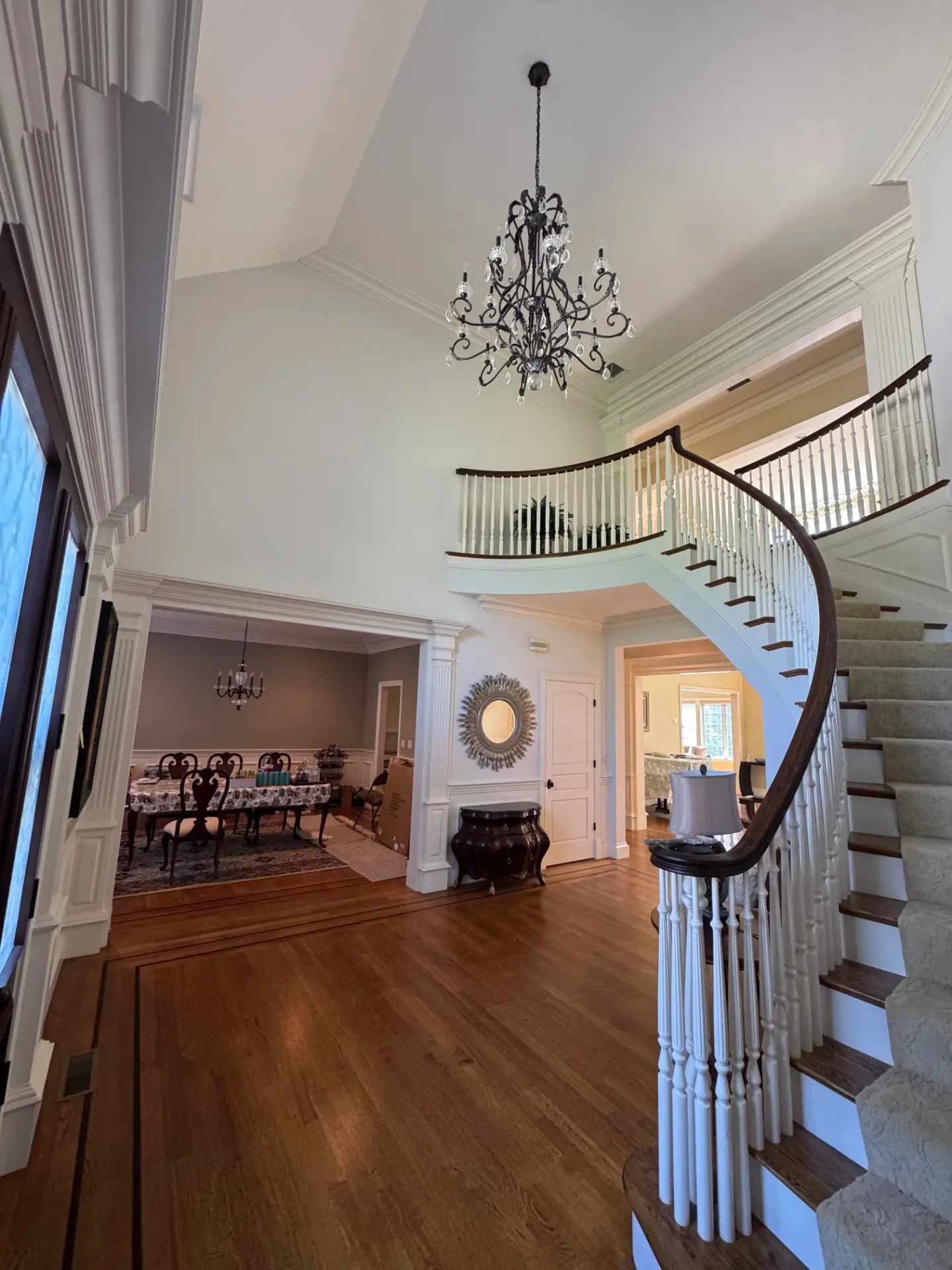 Elegant foyer with curved staircase, chandelier, and crisp white crown molding painted by Elite Brothers Painting in Lowell, Massachusetts